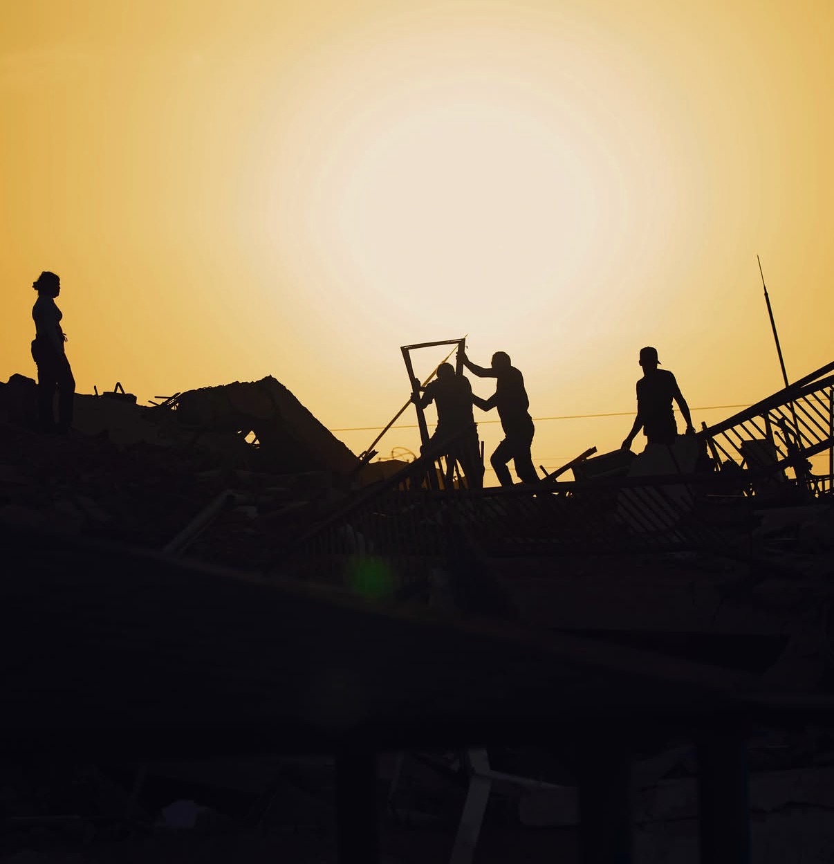 Equipos de rescate trabajando al atardecer entre los escombros.